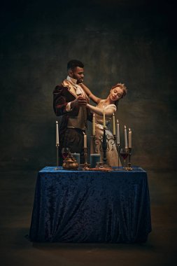 Naiplik çağı. Vikont ve Vikontes, Afrikalı erkek ve sarışın kadın. Dönem kıyafetleri içinde romantik bir akşam yemeği yiyorlar, geçmişe dönük yeşil arka planda dans ediyorlar. Tarih kavramı, mahsul, çağların karşılaştırması