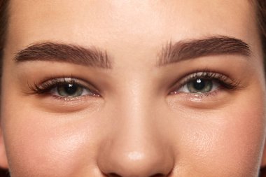 Kadın yüzünün, gözlerinin, kaşlarının, burnunun yakın plan görüntüsü. İyi korunmuş pürüzsüz bir cilt, mükemmel kaşlar. Kırbaç kaplaması. Gülen surat. Doğal güzellik, cilt bakımı, kozmetoloji ve kozmetik ürünleri reklam konsepti