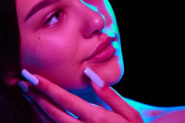 Derin yüz temizleme. Makyajsız, çekici bir genç kızın mükemmel cildini neonlu siyah bir stüdyonun arka planına karşı gösteren görüntüsü. Doğal güzellik, cilt bakımı, gençlik, sağlık konsepti.