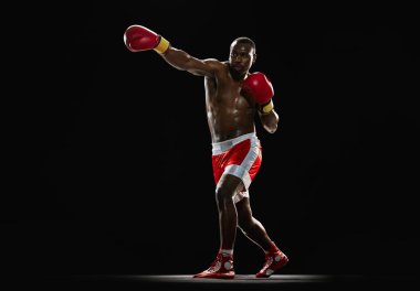 Dinamik duruş. Siyah arka planda izole edilmiş hareketli boksör, atletik güçlü vücudu olan Afrikalı-Amerikalı kaslı bir adam. Profesyonel spor anlayışı, aktif yaşam tarzı, vücut, güç
