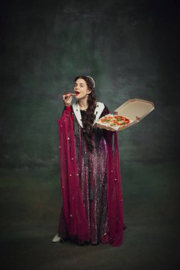 Pizza markaları için komik reklamlar. Genç bir kadının portresi, zengin elbiseli bir kraliyet mensubu, klasik yeşil arka planda pizza yiyor. Tarih kavramı, dönemin karşılaştırması, yeniden yapım, restoran.