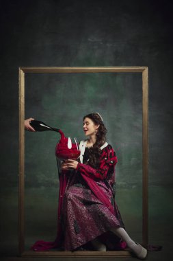 Ortaçağ kraliyet ailesinden genç bir kişinin portresi, altın çerçevenin içinde oturan dev şarap kadehleri eski yeşil arka plana dökülen bir kadın. Tarih kavramı, çağların karşılaştırması, yeniden yapım