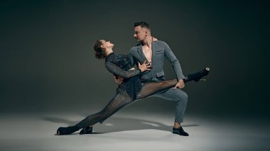 Tutkulu bir performans. Koyu yeşil arka planda dans eden kadın ve erkek, şık bir çift. Dans, performans, sanat, duygu, eğlence kavramı