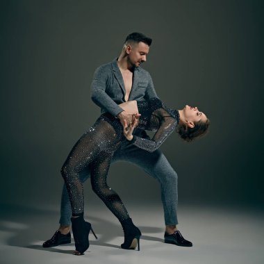 Tutkulu bir performans. Koyu yeşil arka planda dans eden kadın ve erkek, şık bir çift. Dans, performans, sanat, duygu, eğlence kavramı