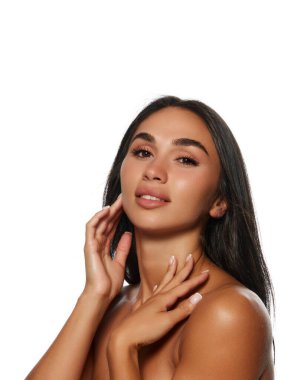 Mükemmel ciltli, çıplak makyajlı, uzun koyu renk saçlı ve beyaz arka planda solgun tenli çekici bir kadın portresi. Kadın güzelliği, deri ve vücut bakımı, kozmetik ve kozmetik kavramı