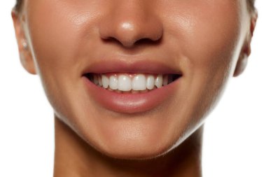 Beyaz arka planda izole edilmiş dişi yüzü, burnu, dudakları ve dişleri. Diş beyazlatma, diş bakımı. Kadın güzelliği, deri ve vücut bakımı, kozmetik ve kozmetik kavramı