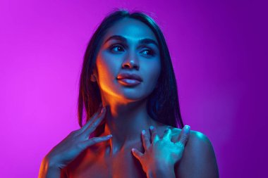 Şehvetli güzellik, estetik. Siyah saçlı çekici bir genç kadın, iyi korunmuş bir ten, mor arka planda dolgun dudaklar. Güzellik, cilt ve vücut bakımı, kozmetik ve kozmetik kavramı