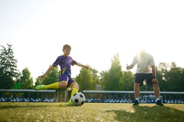 Küçük bir çocuk, mor üniformalı bir çocuk, futbol oyuncusu profesyonel koçla dışarıda antrenman yaparken topa vurmaya odaklanıyor. Spor anlayışı, çocukluk, eğitim, aktif yaşam tarzı
