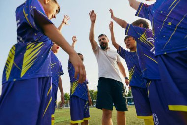 Çocuklar ve antrenörleri birbirine yakın duruyor ve maç başlamadan önce motivasyon ruhu içinde ellerini kaldırıyorlar. Spor, çocukluk, eğitim, başarı, aktif yaşam tarzı kavramı