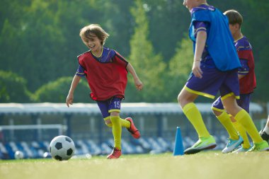 Genç oğlanların dinamik görüntüsü, açık havada futbol antrenmanı yapan çocuklar, topla koşan yeşil kız, zafer için yarışıyor. Spor, çocukluk, eğitim, başarı, aktif yaşam tarzı kavramı