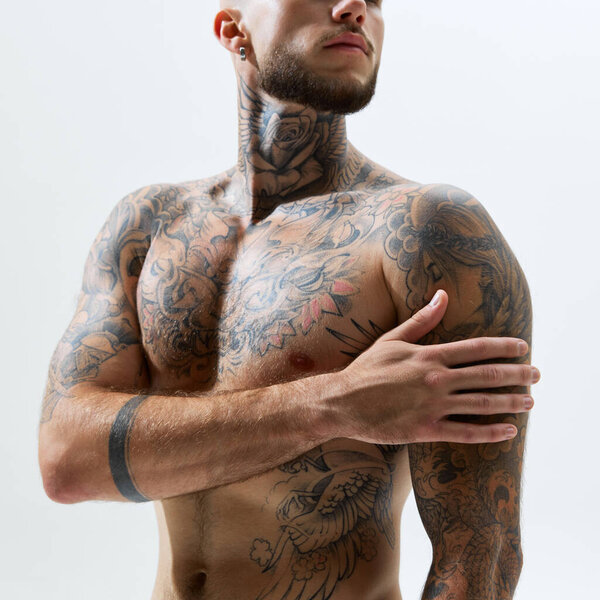 Cropped image of shirtless, sportive, muscular male body with tattoos, strong hands and breast isolated on white studio background. Concept of male beauty, body and health care, sport