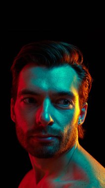 İyi korunmuş derisi ve bakımlı saçı olan yakışıklı bir adamın portresi neon ışıkta siyah stüdyo geçmişine karşı güven gösteriyor. Erkek güzelliği, cilt bakımı, kozmetik, kozmetik