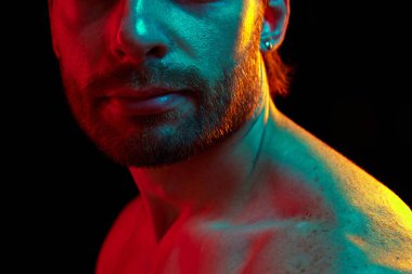 Erkeklerin yakın çekimi daha alçak, pürüzsüz, temiz ve bakımlı bir cilt, modern erkek güzellik standartlarını vurguluyor ve neon ışıklı arka planda siyah stüdyoya karşı cilt bakımı.