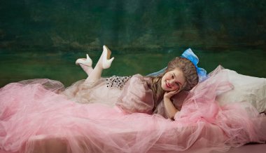 Zarif Dinlenme. Zarif genç kadın, asil insan pembe peçeli yatakta yatıyor ve klasik yeşil arka plana gülümsüyor. Tarihi cazibe. Tarih kavramı, barok sanatı, çağların karşılaştırması.