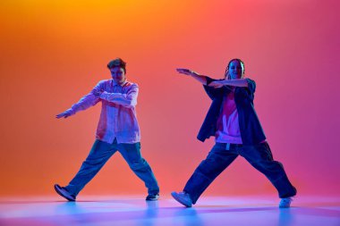 Sanatçı, yetenekli, günlük giysiler içinde genç bir kadın ve erkek neon ışıklarıyla hip-hop dansı yapıyorlar. Çağdaş dans, hobi, gençlik kültürü kavramı