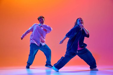Sanatçı, yetenekli, günlük giysiler içinde genç bir kadın ve erkek neon ışıklarıyla hip-hop dansı yapıyorlar. Çağdaş dans, hobi, gençlik kültürü kavramı