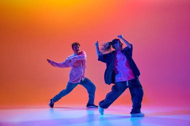 Sanatçı, yetenekli, günlük giysiler içinde genç bir kadın ve erkek neon ışıklarıyla hip-hop dansı yapıyorlar. Çağdaş dans, hobi, gençlik kültürü kavramı