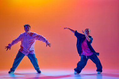 Modern dans stillerinin enerjisi. Genç insanlar, tutkulu erkek ve kadın, neon ışıklarıyla hip-hop dansı yapan gradient stüdyo arkaplanı. Çağdaş dans, hobi, gençlik kavramı