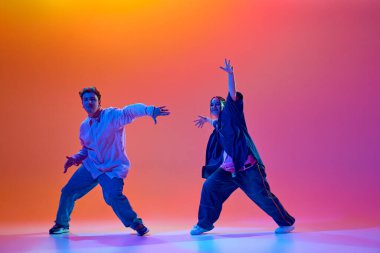 Modern dans okulu. Genç insanlar, gündelik giysiler içinde dans eden kadın ve erkek, neon ışıkta, gradyan stüdyonun arka planına karşı enerjik bir hip-hop dansı yapıyorlar. Çağdaş dans, hobi, gençlik kavramı