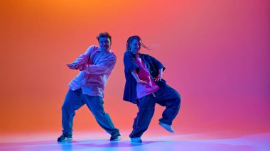 Modern dans okulu. Genç insanlar, gündelik giysiler içinde dans eden kadın ve erkek, neon ışıkta, gradyan stüdyonun arka planına karşı enerjik bir hip-hop dansı yapıyorlar. Çağdaş dans, hobi, gençlik kavramı