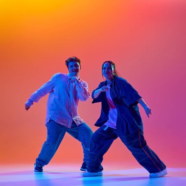 Genç insanlar, erkek ve kadın, modern dans stillerini icra eden dansçılar, neon ışıkta, gradient stüdyo geçmişine karşı hip-hop dansı yapan. Çağdaş dans, hobi, gençlik kavramı