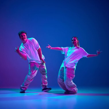 Enerji patlaması. Sanatçı genç sanatçılar, erkek ve kadın hip-hop dansçıları, neon ışıkta mor stüdyo arka planına karşı modern dans becerilerini gösteriyorlar. Çağdaş dans, hobi, gençlik kavramı