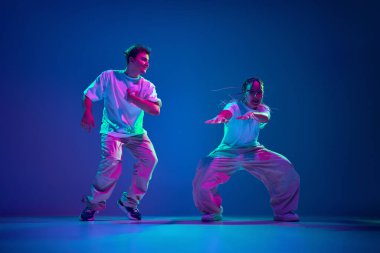 Enerji patlaması. Sanatçı genç sanatçılar, erkek ve kadın hip-hop dansçıları, neon ışıkta mor stüdyo arka planına karşı modern dans becerilerini gösteriyorlar. Çağdaş dans, hobi, gençlik kavramı