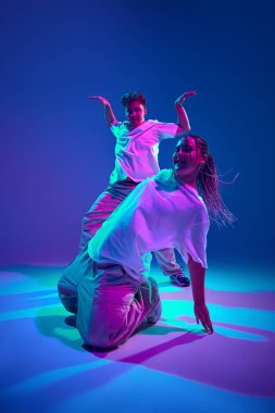 Dinamik performans. Genç adam ve kadın, dansçılar hip-hop dansı yapıyor, neon ışıkta mor stüdyonun arka planına karşı çağdaş dans gösterisine katılıyor. Çağdaş dans, hobi, gençlik kavramı