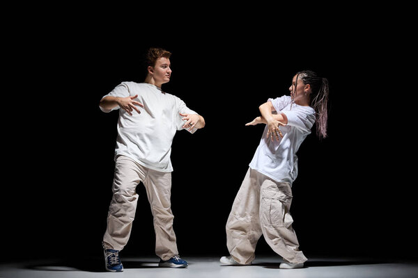 Black and white mix. Young artistic man and woman in stylish casual clothes dancing hip-hop against black studio background. Concept of contemporary dance, hobby, youth, entertainment — Stock Image Black White Mix Young Artistic Man Woman Stylish Casual Clothes Stock Image