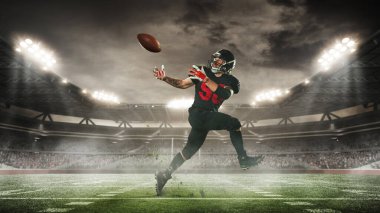 Adamın dinamik görüntüsü, hareket halindeki Amerikan futbolcusu, maç sırasında topa vuruyor, açık hava arenasında, taraftarlar ayakta duruyor. Stadyumun 3 boyutlu görüntüsü. Spor, turnuva, yarışma, oyun kavramı