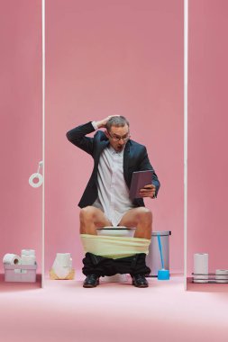 Gergin oyun anı. Duygusal adam, resmi olarak iş adamı tuvalette oturup pembe arka planda canlı futbol maçı izler. Spor, oyun, maç etkinliği, insan duyguları kavramı