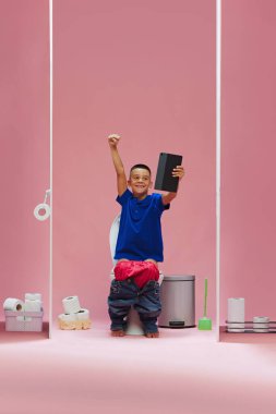 Kazanan oyun. Genç bir çocuk, tuvalette oturan ve tabletten futbol maçı izleyen pembe arka plana karşı duygusal olarak favori takımı destekleyen. Spor, oyun, maç etkinliği kavramı