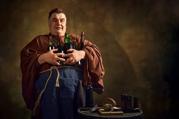 stock image Delightful man, monk holding various bottles filled with beer, ale, and wine against vintage background. Rich heritage of monastic brewing. Concept of comparison of eras, history, brewery, traditions