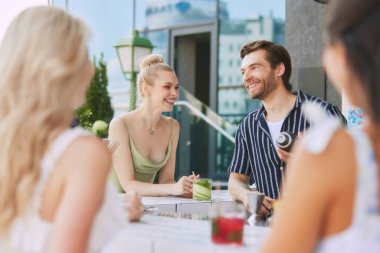 Titreşimli erkek barmenle neşeli sohbetin tadını çıkaran mutlu, gülümseyen genç sarışın kadına odaklan. Açık hava barı atmosferi. Arkadaşlık kavramı, parti, eğlence, kutlama, rahatlama.