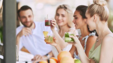 Bar titreşimleri. Mutlu, gülümseyen genç insanlar, kadın ve erkek ferahlatıcı içeceklerin keyfini çıkarıyorlar, modern açık hava barında nefis bir kokteyl. - Şerefe. Arkadaşlık kavramı, parti, eğlence, kutlama, rahatlama.