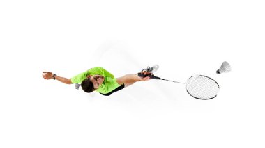 Genç bir adamın hava görüntüsü, yeşil tişörtlü badminton oyuncusu ve hareket halinde siyah şortlu, odaklı eğitim almış, beyaz arka planda izole edilmiş. Spor anlayışı, rekabet, aktif ve sağlıklı yaşam tarzı