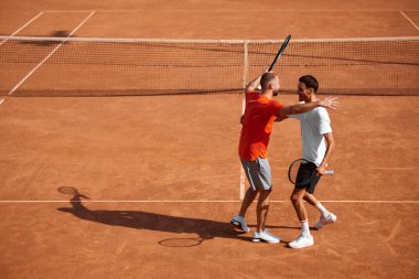 Mutlu pozitifler, arkadaşlar, tenis oyuncuları açık havada oynanan yoğun maçtan sonra birbirlerini kucaklıyorlar. Karşılıklı saygı. Spor anlayışı, rekabet, aktif ve sağlıklı yaşam tarzı