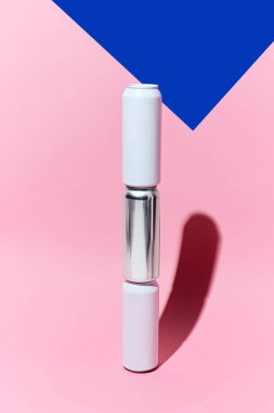 Pembe arka plana yerleştirilmiş üç alüminyum teneke kutunun yaratıcı minimalist maketi. Bira, limonata, enerji içecekleri, kokteyller, soda. Ürün markalaşması için basit ve şık bir temel