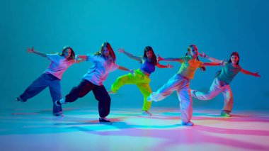 Dinamik dansla kendini ifade etmek. Genç kızlar, sahnede hip hop yapan gençler neon arka planda siyan mavisi arka plana karşı. Modern dans stilleri, gençlik kültürü, aktif yaşam tarzı kavramı