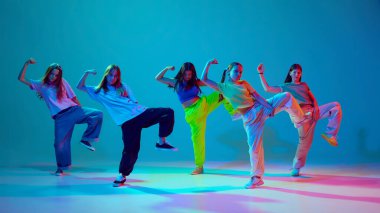 Enerjiyi ve kişiliği çağrıştırıyor. Sanatçı, hareketli yetenekli kızlar, neon arka planda Cyan mavisi arka planda hip hop dansı yapıyorlar. Modern dans stilleri, gençlik kültürü, aktif yaşam tarzı kavramı