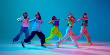 Enerjik, sanatsal genç kızlar, neon arka planda Cyan mavisi arka planda hip hop dansı yapıyorlar. Modern dans stilleri, gençlik kültürü, aktif yaşam tarzı kavramı