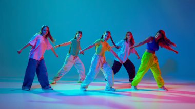 Yetenekli bir grup çocuk, neon arka planda siyan mavisi arka planlarına karşı keskin hip hop hareketleriyle ritmini ve stilini sergiliyor. Modern dans stilleri, gençlik kültürü, aktif yaşam tarzı kavramı