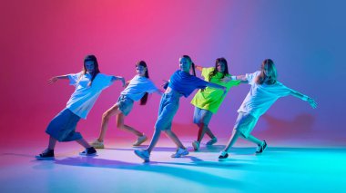 Bir grup enerjik çocuk hip hop yeteneklerini sergiliyorlar, neon ışıkta değişen pembe arka planda dans ediyorlar. Modern dans stilleri, gençlik kültürü, aktif yaşam tarzı kavramı