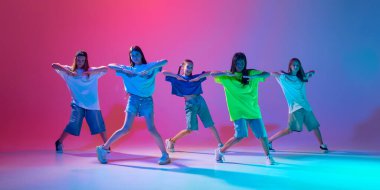 Çocuklar yüksek enerjili bir hip hop dansı yaparak, neon ışıkta değişen pembe arka plana karşı senkronize olma becerilerini sergiliyorlar. Modern dans stilleri, gençlik kültürü, aktif yaşam tarzı kavramı