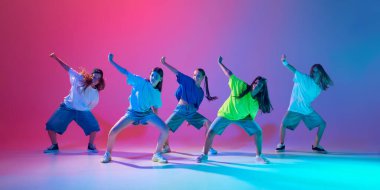 Çocuklar yüksek enerjili bir hip hop dansı yaparak, neon ışıkta değişen pembe arka plana karşı senkronize olma becerilerini sergiliyorlar. Modern dans stilleri, gençlik kültürü, aktif yaşam tarzı kavramı