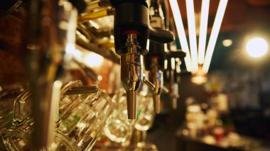 Arka planda boş bardak sıraları ve bar tezgahı ile bulanık arka plan karşı ayarlanmış, birden fazla parlak bira muslukları yakın çekim. Bira, bira fabrikası, bar, Ekim Festivali