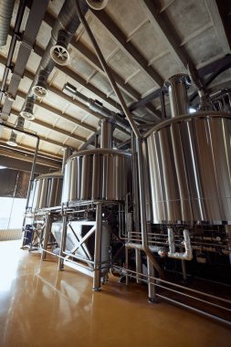 Birkaç paslanmaz çelik fermantasyon tankı ve boruları olan, boru ve vanalardan oluşan bir ağ ile birbirine bağlı, büyük, modern bir bira fabrikası. Bira, bira fabrikası, üretim, kalite kontrol kavramı