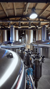 Endüstriyel demleme tankları, yüksek kaliteli bira yapımında kullanılan gelişmiş ekipmanları yansıtacak şekilde hazır bekliyor. Bira, bira fabrikası, üretim, kalite kontrol kavramı