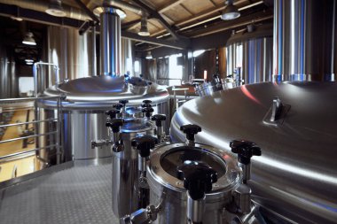 Bira fabrikasındaki tankların ve vanaların parlak yüzeyleri bira yapımındaki temizlik ve hassasiyetin yüksek standartlarını gösteriyor. Bira, bira fabrikası, üretim, kalite kontrol kavramı