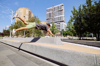 Uçuşun ortasında yakalanmış, beton bariyerin üzerinden atlayan, şehrin göbeğindeki korkusuz parkçı ruhu somutlaştıran genç bir atletik. Aktif ve sağlıklı yaşam tarzı kavramı, gençlik kültürü